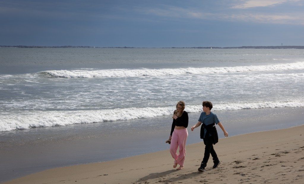 Waves rolling onto Old Orchard Beach shoreline with kids walking