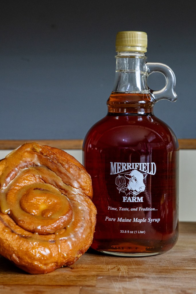 Bottle of Merrifield Farm maple syrup with a maple cinnamon roll
