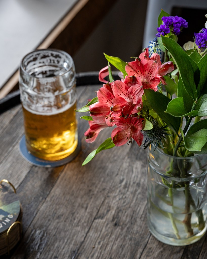 Pilsner with flowers on wooden barrel