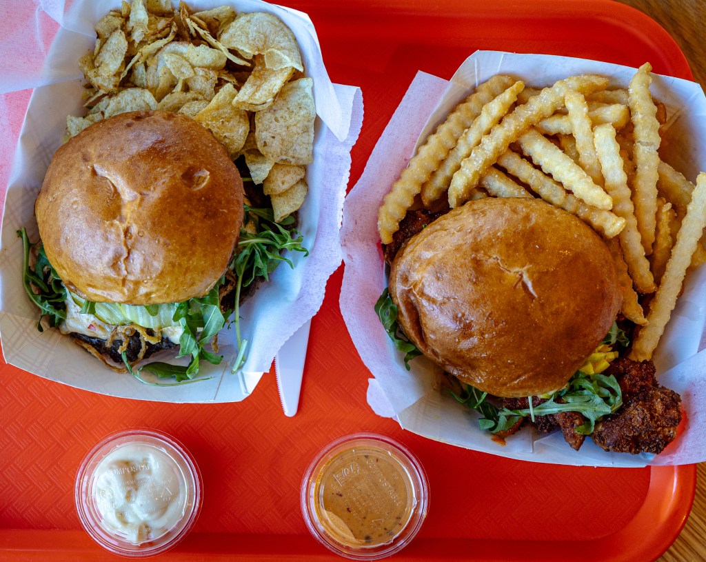 Overhead view of two sandwiches with fries and chips on tray

