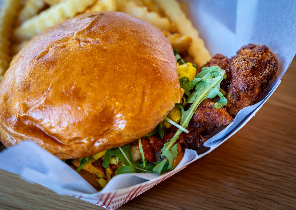Close-up of fried chicken sandwich with arugula on brioche bun

